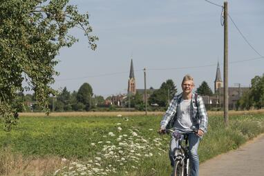 Vergrößerte Ansicht von Radfahrer auf einem Feldweg im Hintergrund die beiden Friedrichsfelder Kirchen