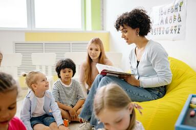 Vergrößerte Ansicht von Frau liest Kindern ein Buch vor