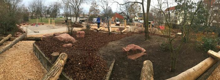 Vergrößerte Ansicht von Der Spielplatz in der Rudolf-Maus-Straße wurde saniert und im Februar 2022 wieder geöffnet. Das Ergebnis der Sanierung ist ein abenteuerlicher Spielplatz mit vielen Bäumen, Sträuchern und Spielelementen aus Steinen und Baumstämmen. Kinder und Eltern waren an der Planung beteiligt.