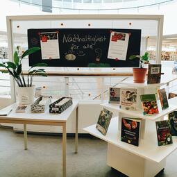 Vergrößerte Ansicht von Die Präsentation des Angebots "Säen &amp; Ernten". Die Boxen, in denen sich das Saatgut befindet und eine Buchausstellung.