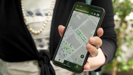 Vergrößerte Ansicht von Die Erste Bürgermeisterin Frau Prof. Dr. Pretzell präsentiert die App auf einem Smartphone.