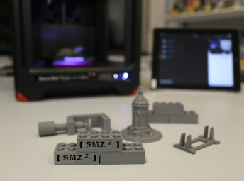 Vergrößerte Ansicht von 3D Drucker mit iPad und ausgedruckten Exponaten