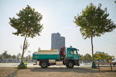 Vergrößerte Ansicht von Ein Tankwagen steht zum Bewässern zwischen zwei frisch gepflanzten Bäumen