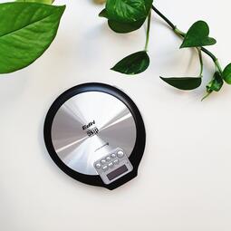 Vergrößerte Ansicht von Bild eines tragbaren CD-Players, ohne Kopfhörer, in den Farben Silber und Schwarz. Im Hintergrund sind grüne Pflanzenblätter zu sehen.