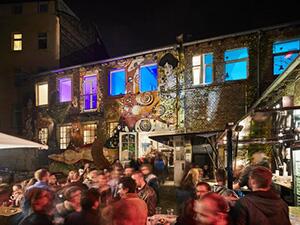 Viele Menschen in einem Hinterhof mit schöner Beleuchtung im Jungbusch