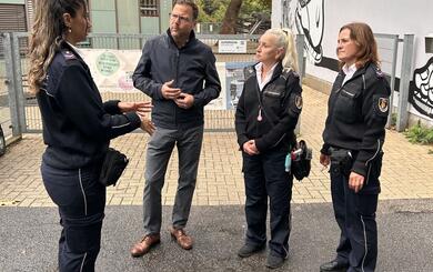 Sicherheitsbürgermeister Dr. Volker Proffen im Gespräch mit Mitarbeiterinnen des Ordnungsdienstes vor dem Eingang der Uhlandschule.