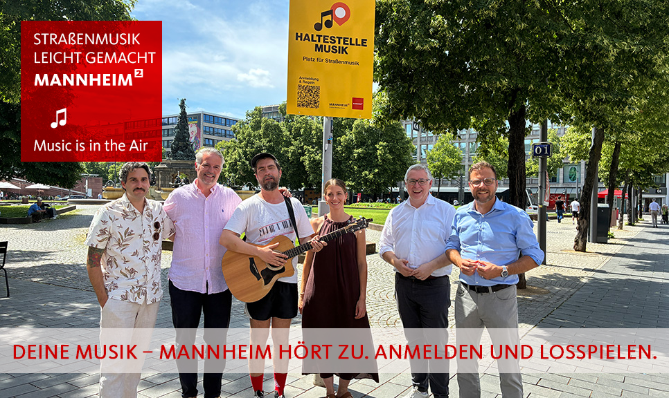 Straßenmusikant und Menschen vor Haltestellenschild