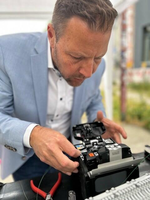 Bürgermeister Dr. Proffen legt selbst Hand an und hilft beim Spleißen der Glasfaserkabel.
