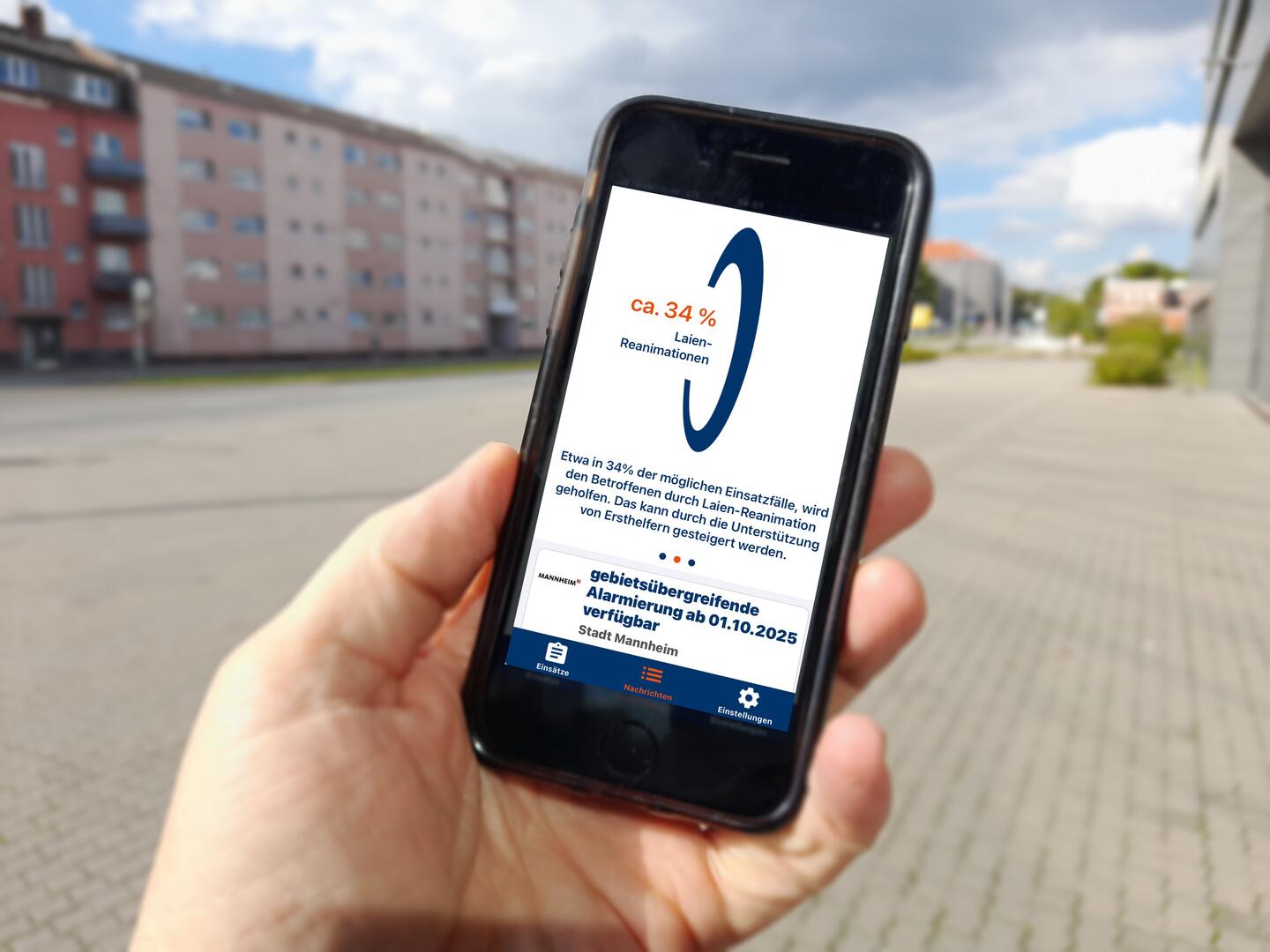 Eine Hand hält ein Handy. Der Bildschirm zeigt die App Katretter mit einem Hinweis zur Laien-Reanimation