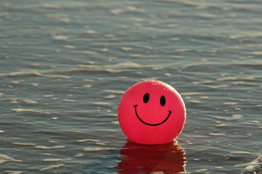 Vergrößerte Ansicht von Pinker kleiner Ball mit lachendem Smilygesicht in Wasserpfütze