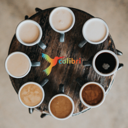 Vergrößerte Ansicht von Bild eines runden Tischs von oben mit Tassen mit unterschiedlich starkem Kaffee
