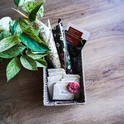 Vergrößerte Ansicht von Foto einer Box mit Saatgut, Flyern, einer Pflanze und buntem Papier mit Blumenaufdruck