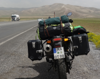 Vergrößerte Ansicht von Abgestelltes Motorrad, im Hintergrund ist ein Bergmassiv erkennbar