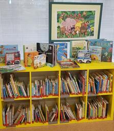 Vergrößerte Ansicht von Foto aus der Zweigstelle Herzogenried, man sieht ein gelbes Bücherregal voller Bilderbücher für Kleinkinder.
