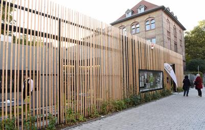 Vergrößerte Ansicht von Mit dem 2021 neue eröffneten Jugendtreff erhalten die Angebote für Jugendliche im Stadtteil einen festen eigenen Standort. Die Angebote und die Ausgestaltung des Jugendtreffs konnten im Rahmen eines Beteiligungsprojektes von den Jugendlichen mitbestimmt und mitgestaltet werden. Ganz im Sinne einer nachhaltigen Stadtentwicklung ist auch die architektonische Umsetzung des Gebäudes mit der begrünten Fassade und der Photovoltaikanlage zur Stromerzeugung.