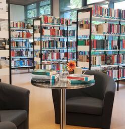 Vergrößerte Ansicht von Offene Bücherregale und eine Leseecke mit zwei schwarzen Sesseln 