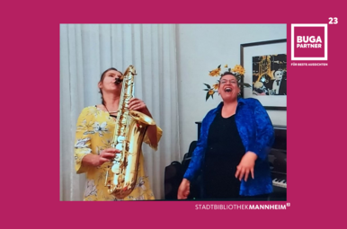 Vergrößerte Ansicht von Foto von Isabelle Specht (Vocals) und Franziska Pertzborn (Saxophon und Handpan). Sie stehen nebeneinander und musizieren bzw. singen.
