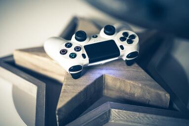 Vergrößerte Ansicht von weißer PS4-Controller auf einem Holzstern liegend