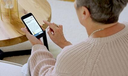 Vergrößerte Ansicht von Eine ältere Dame hält ein Smartphone in der Hand 