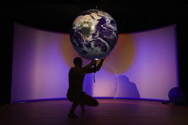Vergrößerte Ansicht von Uwe Topmann hält eine Taschenlampe von unten an eine Weltkugel
