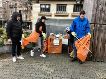 Vergrößerte Ansicht von Das Foto zeigt drei Personen, die sich an einer der Materialausgabe-Stationen in der Neckarstadt für den Cleanup ausrüsten.