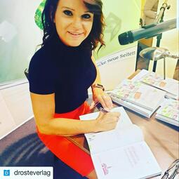 Vergrößerte Ansicht von Nina Badelt unterschreibt ein Buch.