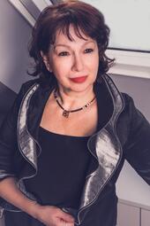 Vergrößerte Ansicht von Ein Foto der Sängerin und Pianistin Lola Demur. Ihre dunklen Augen werden von schwarzen Lidstrichen gerahmt. Ihr dunkles Haar ist gestuft und reicht ihr hinten bis in den Nacken.