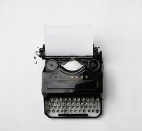 Vergrößerte Ansicht von Eine Schreibmaschine von oben fotografiert. Ein Blatt ist eingelegt.