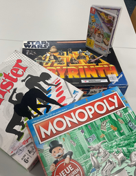 Vergrößerte Ansicht von Drei Brettspiele und ein Videospiel für die Nintendo Switch auf einem weißen Tisch.