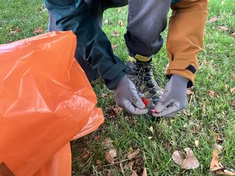 Vergrößerte Ansicht von Ein Mann hebt mühsam Plastik-Konfetti von einer Wiese auf.