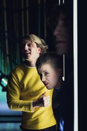 Vergrößerte Ansicht von Robin Krakowski (Tom), Camille Dombrowsky (Nora) und Rocco Brück (Helge) lugen um eine Ecke und betrachten etwas in der Ferne.