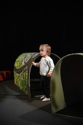 Vergrößerte Ansicht von Ein Kleinkind steht zwischen zwei Pappbögen.