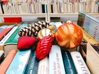 Vergrößerte Ansicht von Ein Foto von Weihnachtsbaumschmuck auf Bücherreihen.