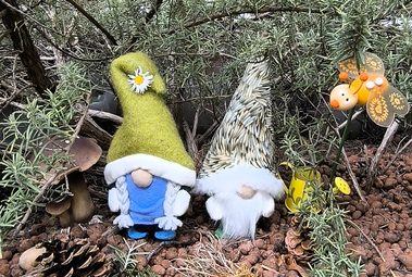 Vergrößerte Ansicht von Zwei Wichtelfiguren unter einem Rosmarinstrauch. Die Zipfelmützen der Wichtel sind doppelt so lang wie ihre Körper und bis über ihre Augen runtergezogen.