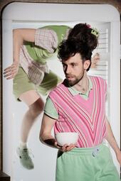 Vergrößerte Ansicht von Moritz Andrea Bürge und Nele Christoph treten aus einem Kühlschrank. Moritz hält eine Schüssel und schaut nach links zum Publikum.