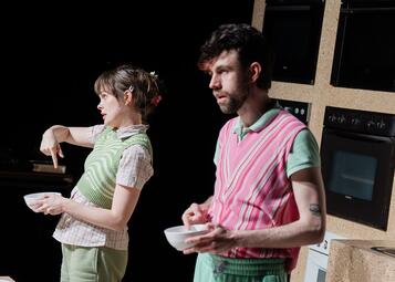 Vergrößerte Ansicht von Nele und Moritz stehen zum Publikum gerichtet und zeigen in ihre Schüsseln, die sie vor sich halten.