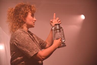 Vergrößerte Ansicht von Das Zelt ist spärlich orange erleuchtet. Das Innere des Zeltes ist leer; die Silhouette von Nadja Rui ist auf der Zeltwand zu erkennen.