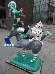 Vergrößerte Ansicht von Eine bunte Plastik der Bremer Stadtmusikanten-Tiere vor einem öffentlichen Gebäude. Jedes der Tiere liest ein Buch.