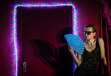 Vergrößerte Ansicht von Ein Mann mit Fächer steht vor einer beleuchteten Tür.