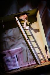 Vergrößerte Ansicht von Person auf einer Leiter in einem Raum mit Heizkörper und Steckdose an der Wand