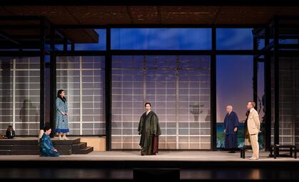 Vergrößerte Ansicht von Bühnenbild mit fünf Personen in traditioneller und moderner Kleidung vor großem Fenster mit Gittermuster in einem japanisch inspirierten Raum