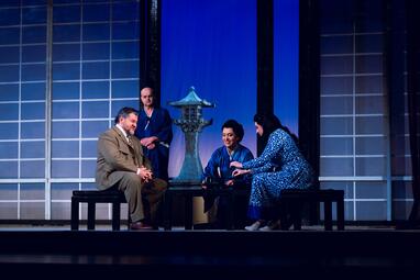 Vergrößerte Ansicht von Vier Personen sitzen auf einer Bühne vor einem japanisch inspirierten Hintergrund mit einem Laternenornament