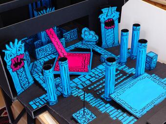 Vergrößerte Ansicht von Modell einer Bühne mit blauen Säulen, dekorativen Elementen und schwarzen Details in einem Raum