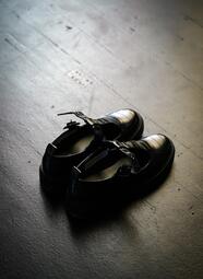 Vergrößerte Ansicht von Paar schwarzer Lederschuhe mit Schnallen auf dunklem Boden