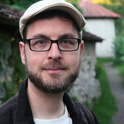 Vergrößerte Ansicht von Ein Foto von Kai Rohlinger.  Er trägtz Schiebermütze, Brille und einen kurzen Vollbart.