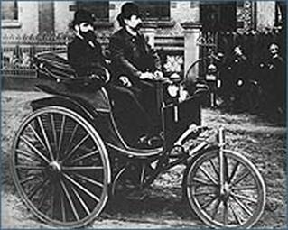 Vergrößerte Ansicht von Karl Benz (rechts) in seinem dreirädrigen Motorwagen