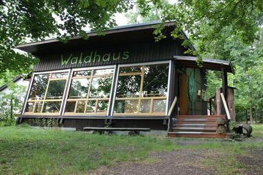 Vergrößerte Ansicht von Einstöckige Hütte mit großer Fensterfront, darüber der Schriftzug &quot;Waldhaus&quot;
