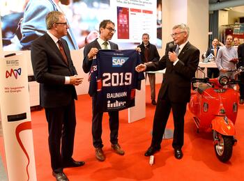 Der Maimarktrundgang führte auch an den Stand der MVV, wo Staatssekretär Baumann ein Trikot der Adler erhielt.