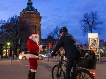 Vor dem Mannheimer Wasserturm übergibt ein Nikolaus Geschenke an einen Radfahrer.