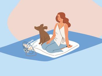 Eine Frau sitzt gemeinsam mit einem Hund auf einer Picknickdecke.